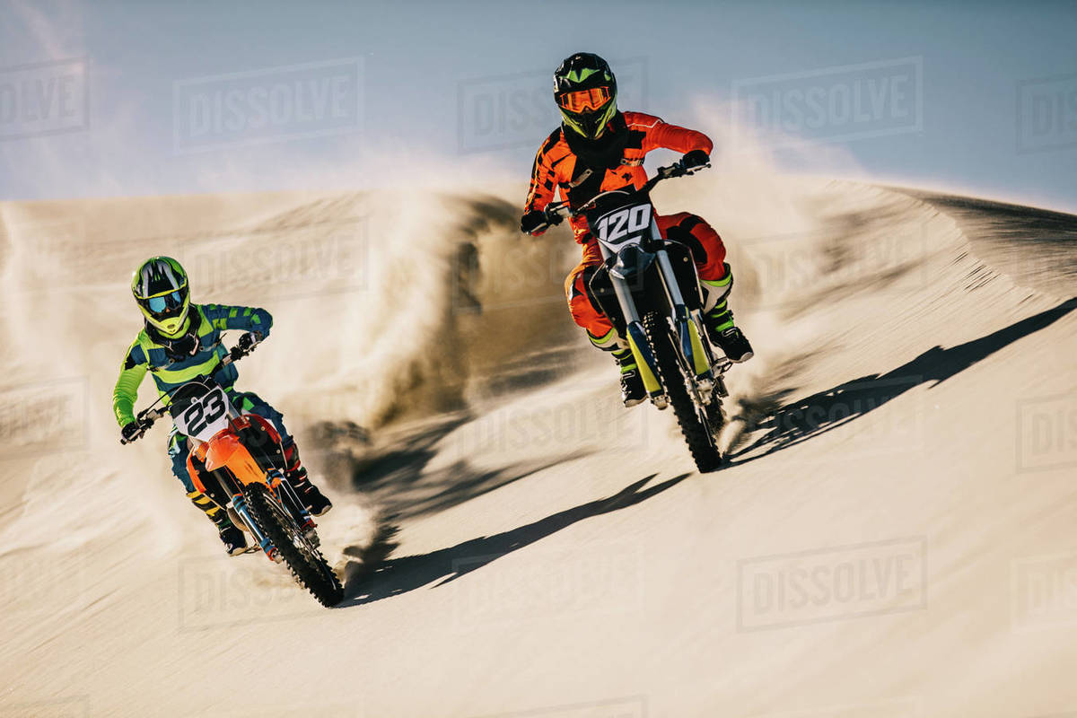 Motorcycle riders in action in desert. Motocross bikes doing full speed