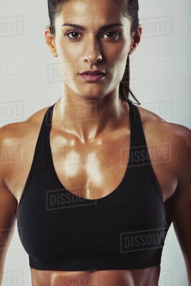 Close up image of young woman in sports bra looking at camera against