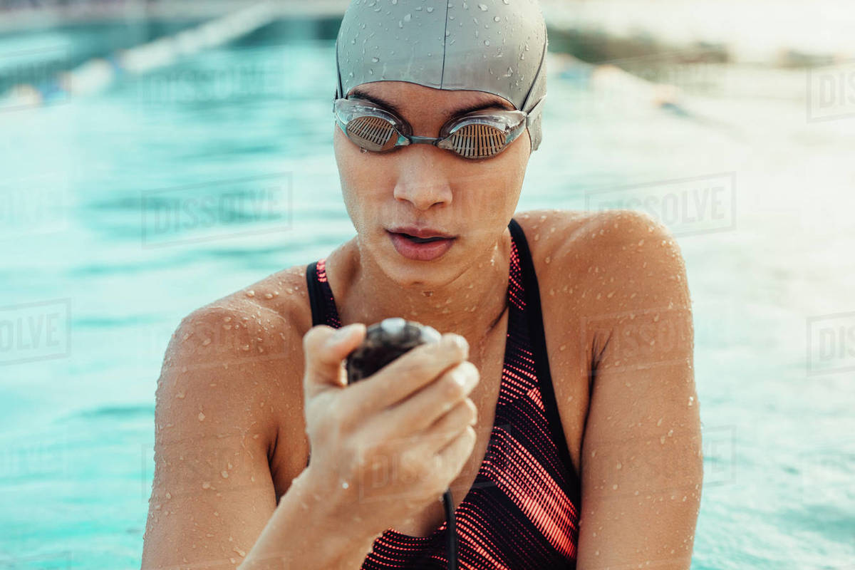 Female swimmer checking a stopwatch after a lap. Woman in swimwear