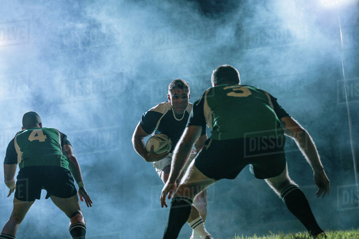 Professional rugby player runs with a ball and opponent team players