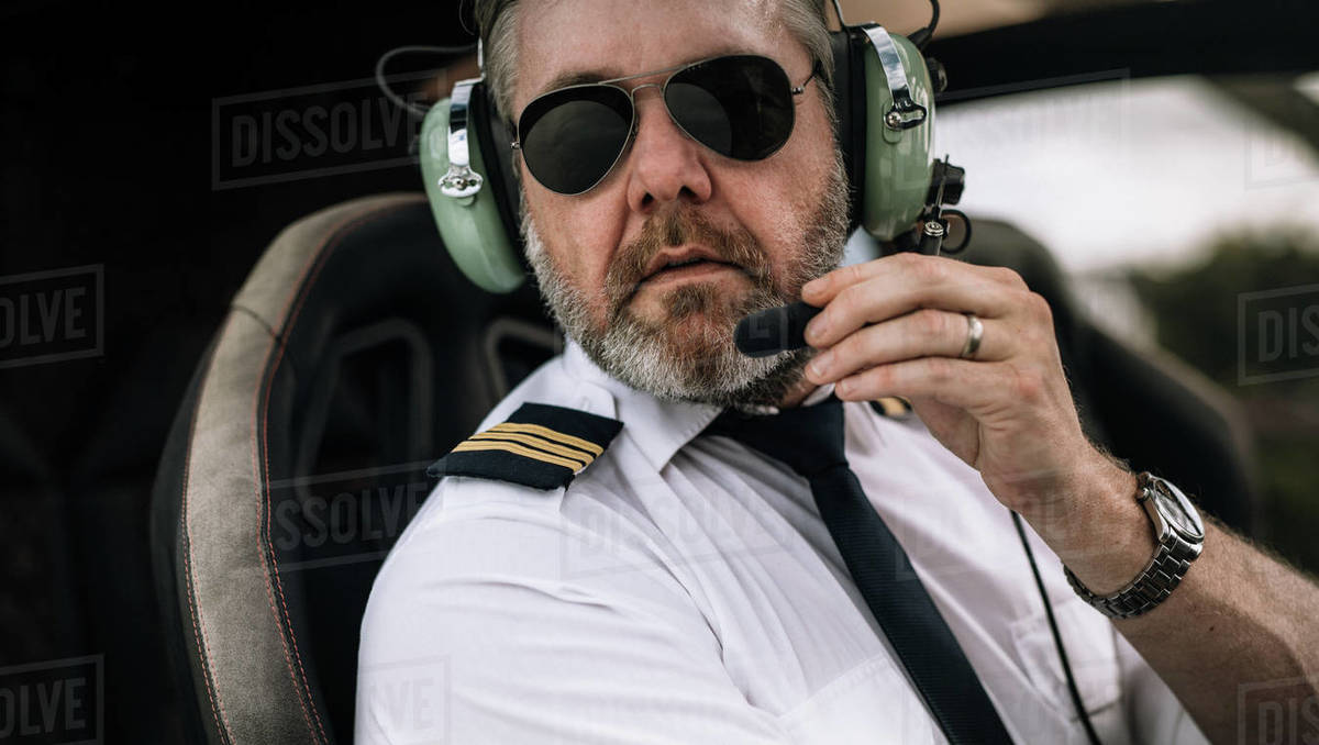 Mature male helicopter pilot with headset in the private helicopter