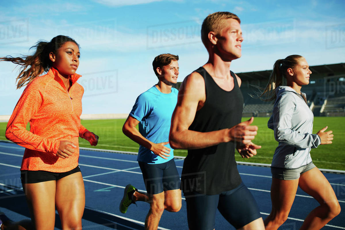 Group of multiracial professional athletes practicing running in stadium. Male and female