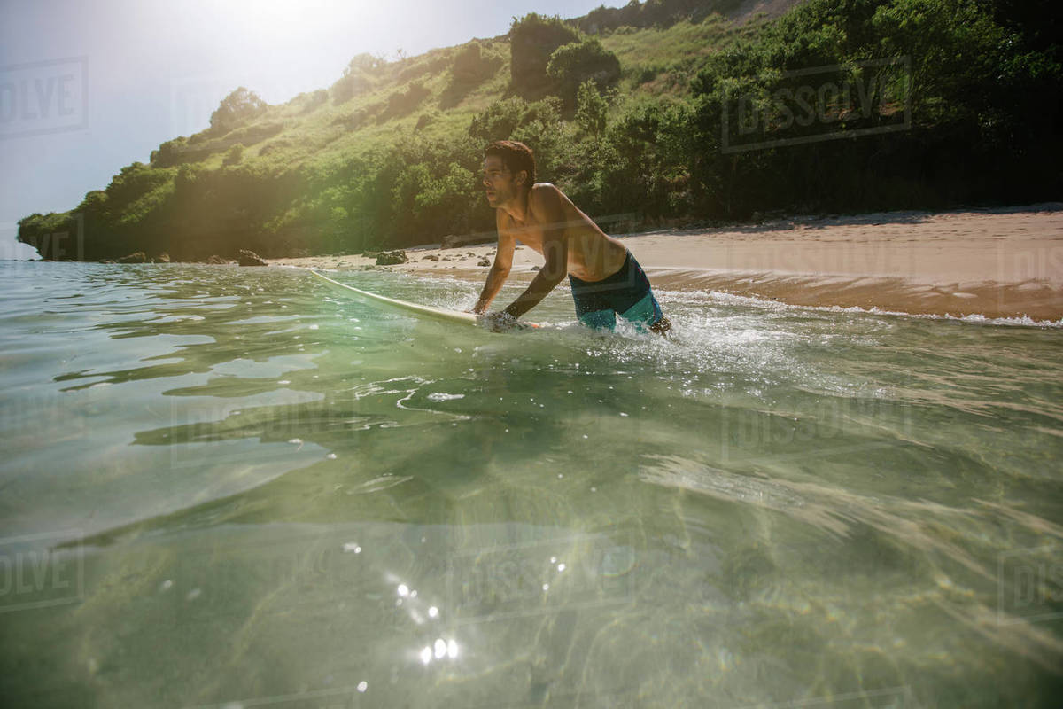 Shot of male surfer in the ocean water with surf board. Young man surfing in sea water. Royalty-free stock photo