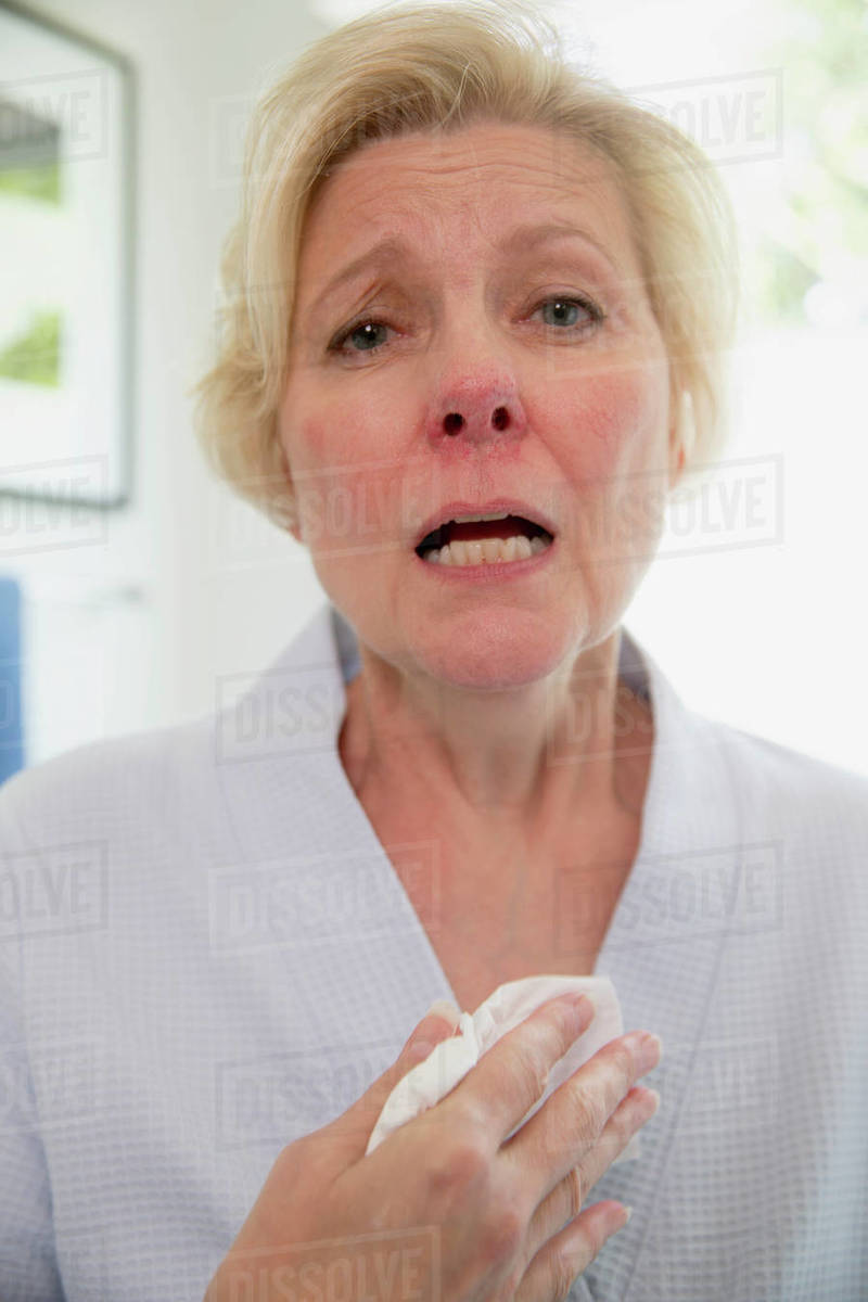 Sick senior Caucasian female sitting on side of bathtub getting ready to fill it for a bath