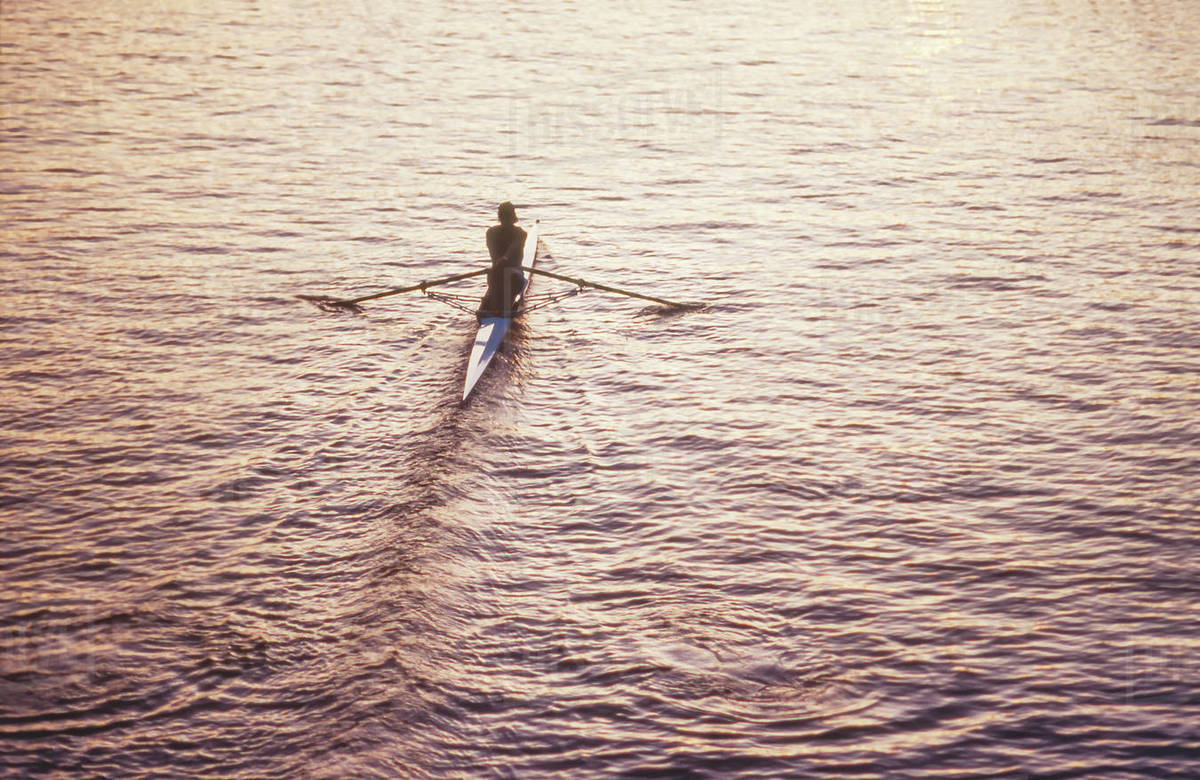 Rower in single skull rowing on calm water Stock Photo Dissolve