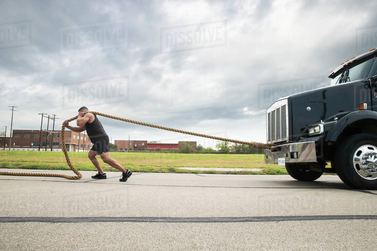 Muscular Hispanic man wearing tank top, Pulling semi truck with large ...