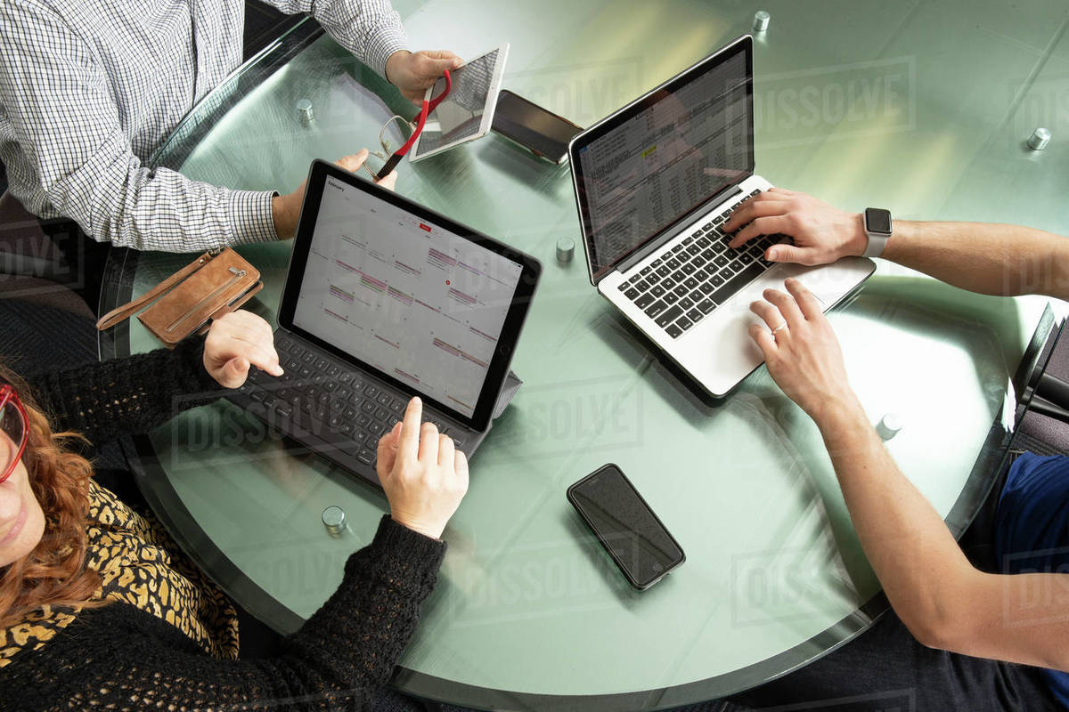 Overhead shot of three people working on there computers and tablets