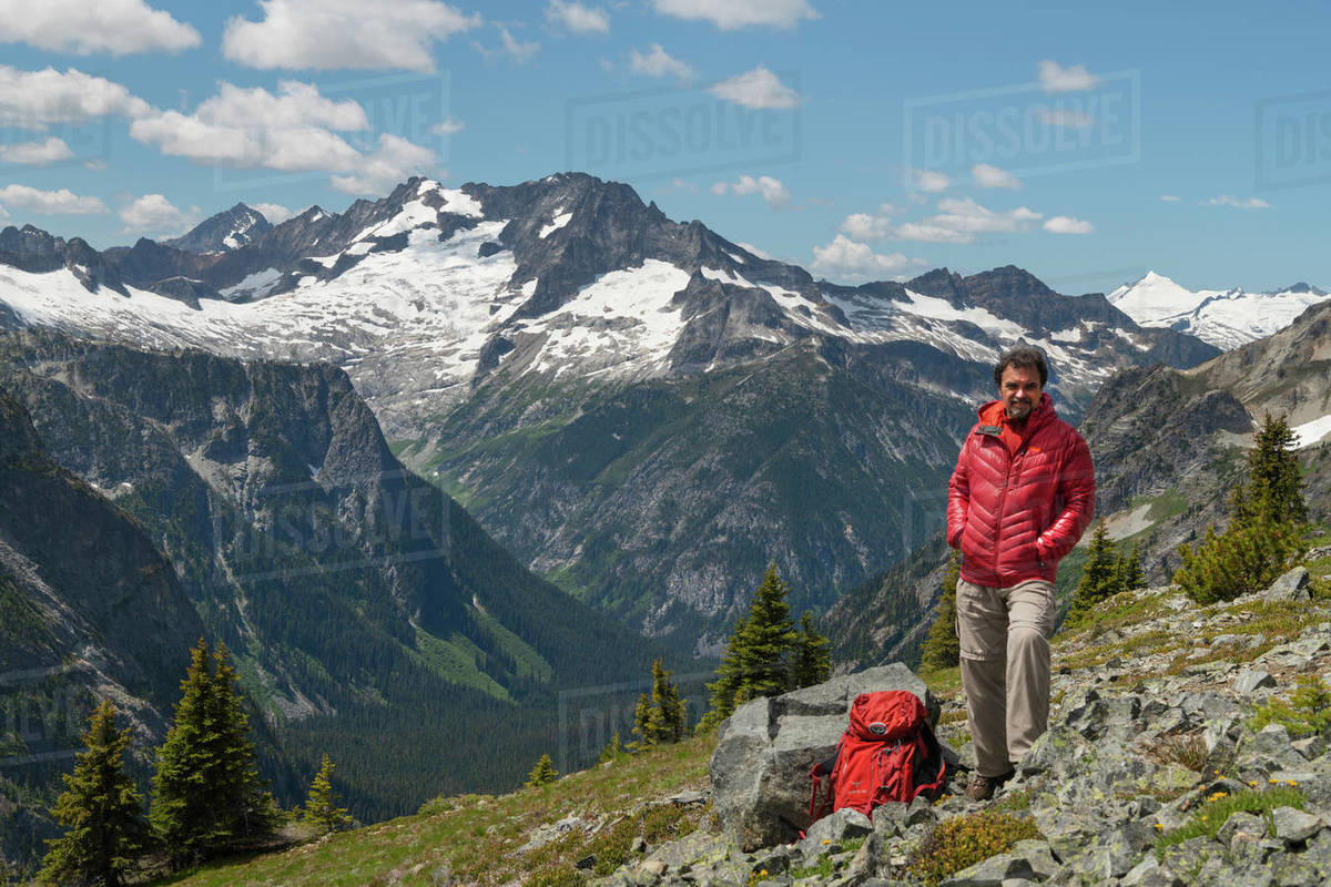 Adult male hiker with red jacket and backpack relaxing on Ragged Ridge ...