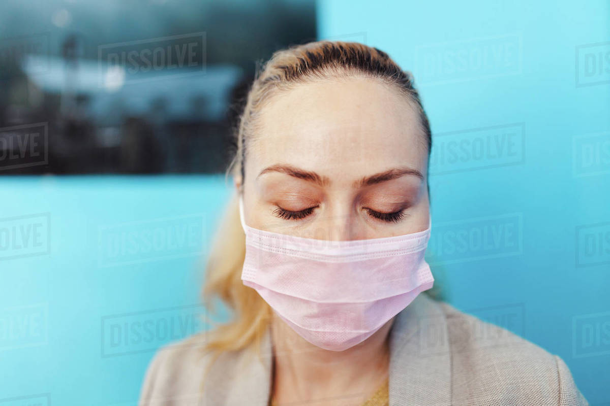 Woman wearing surgical mask with covid 19 model in her hand Stock Photo Dissolve