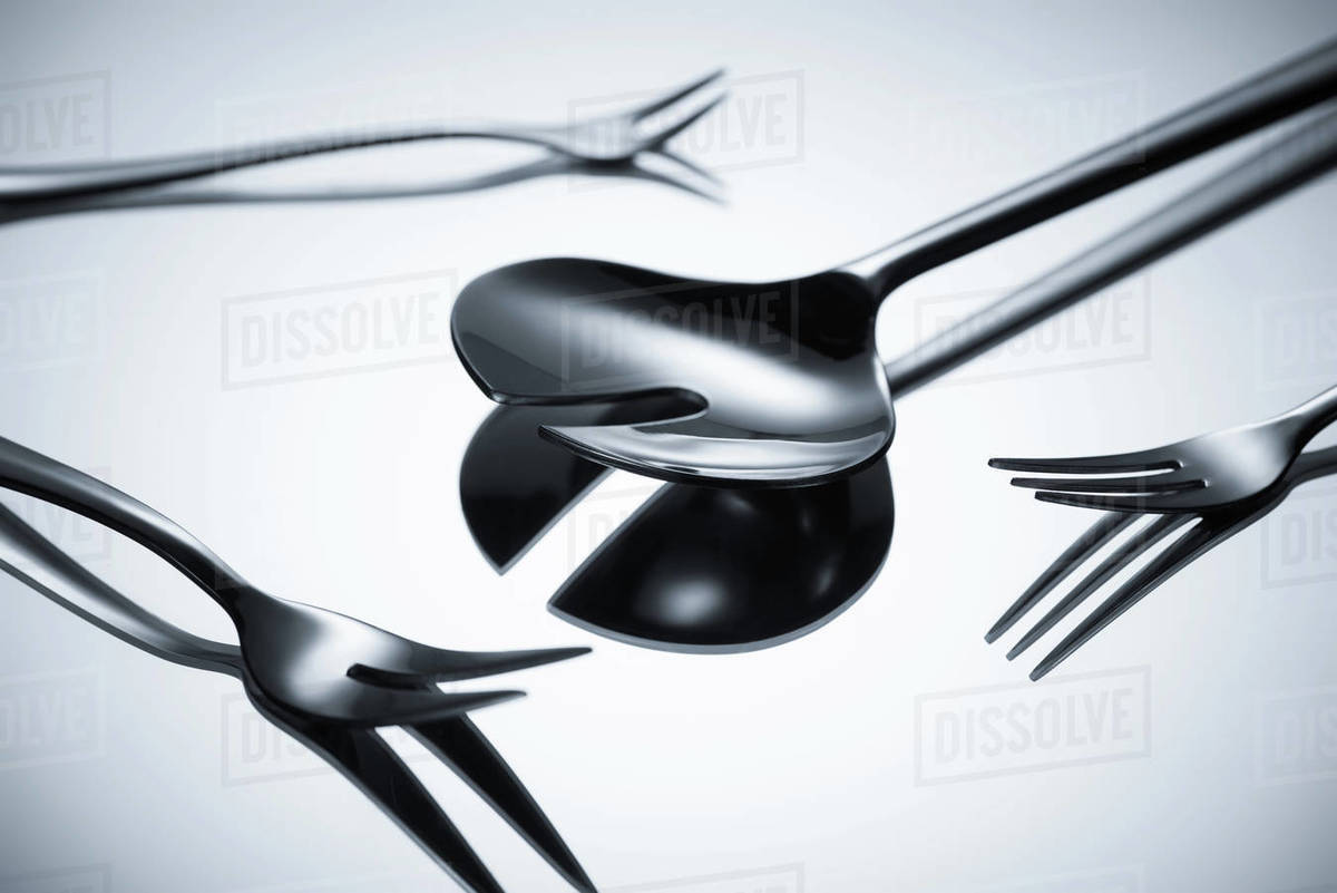 Closeup view of shiny stainless steel cutlery reflected on grey