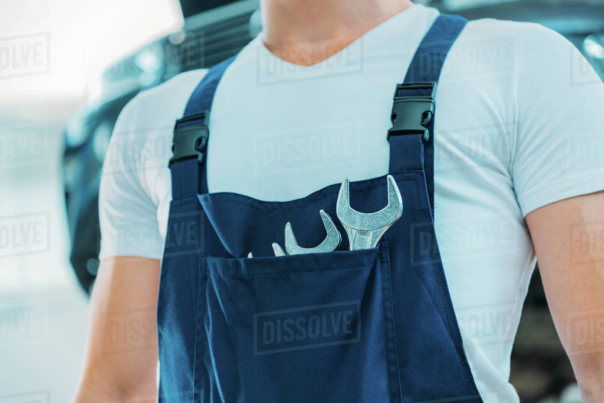 Cropped shot of a car mechanic in overalls with tools in his front