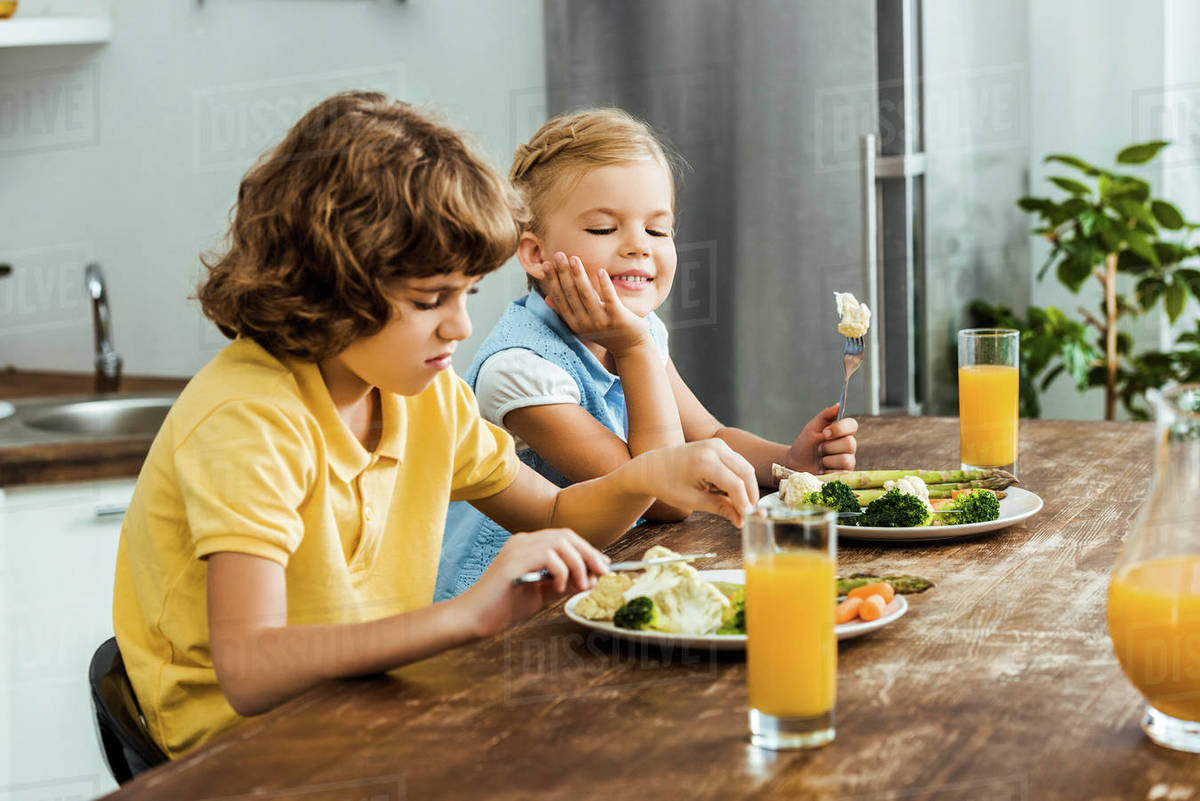 Children eating healthy vegetables and drinking juice together Stock