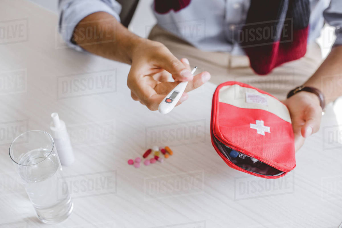 Cropped image of sick manager in scarf holding first aid kit and ...