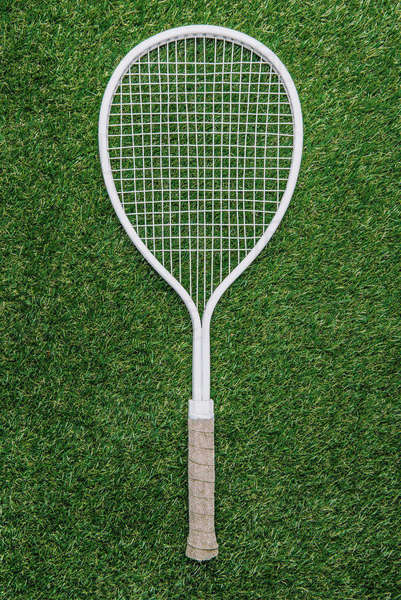 top view of white tennis racket lying on green grass - Royalty-free ...