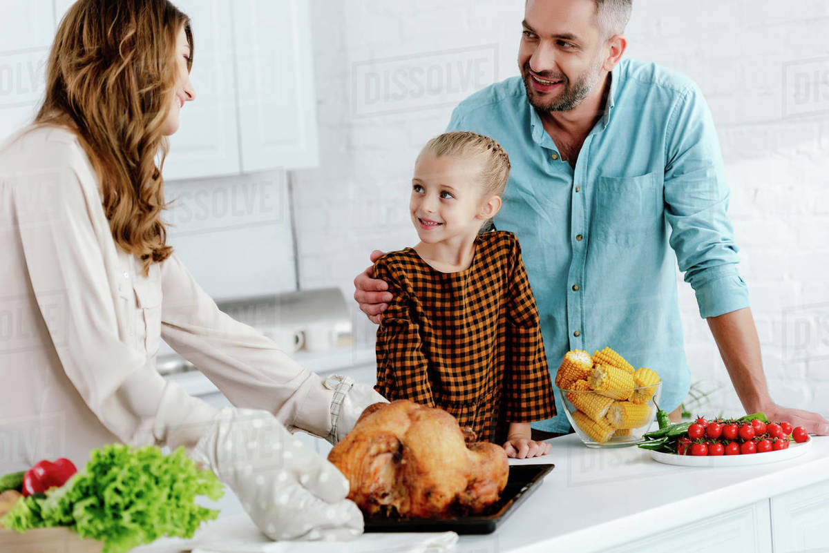 Happy little child preparing thanksgiving dinner with parents - Stock