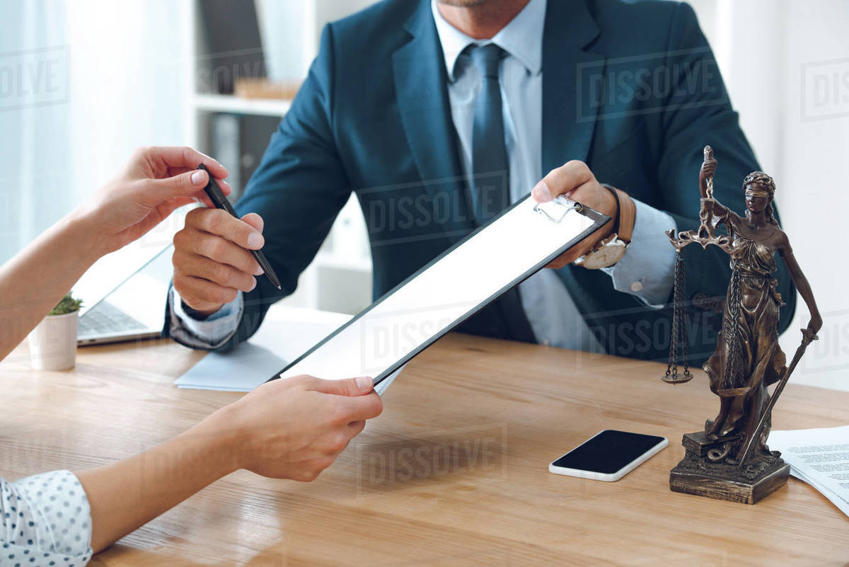 Cropped shot of lawyer giving clipboard and pen to young woman in