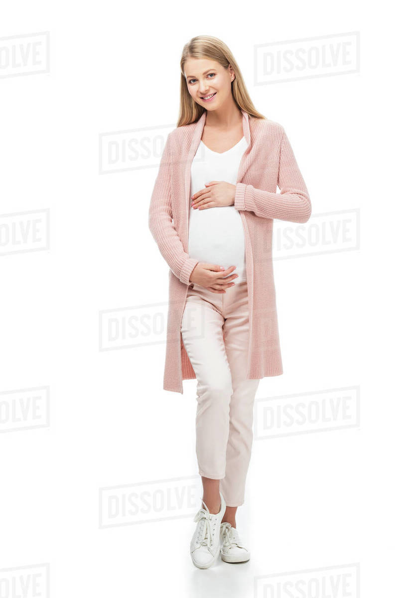 Full length of pregnant woman in pink cardigan touching belly