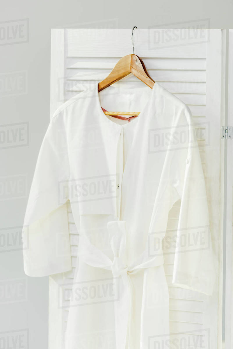 close up of elegant white dress hanging on wooden room divider isolated