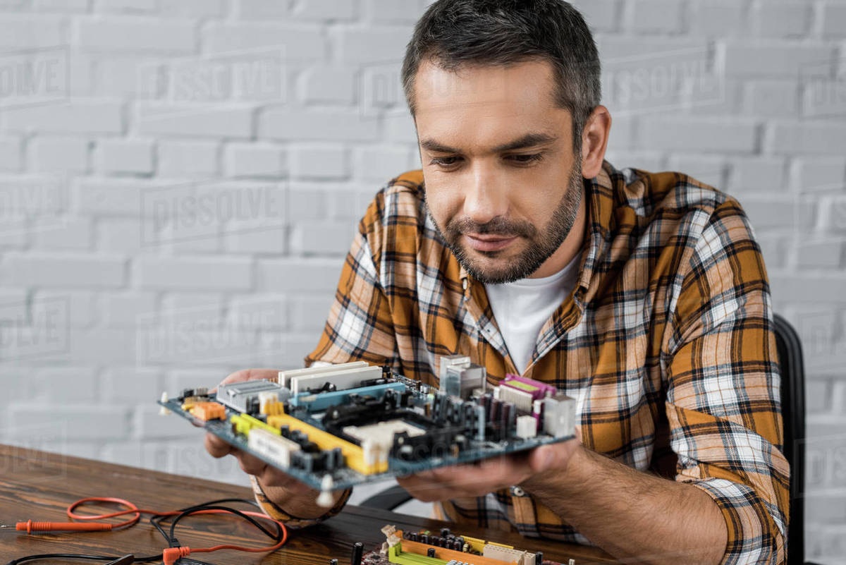 Serious handsome computer engineer holding motherboard Stock Photo