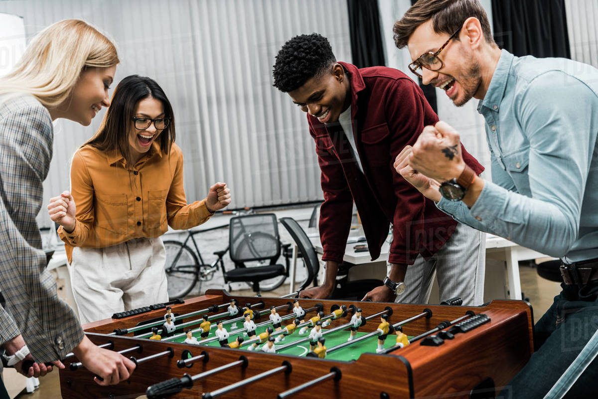 Multicultural business colleagues playing table football together in