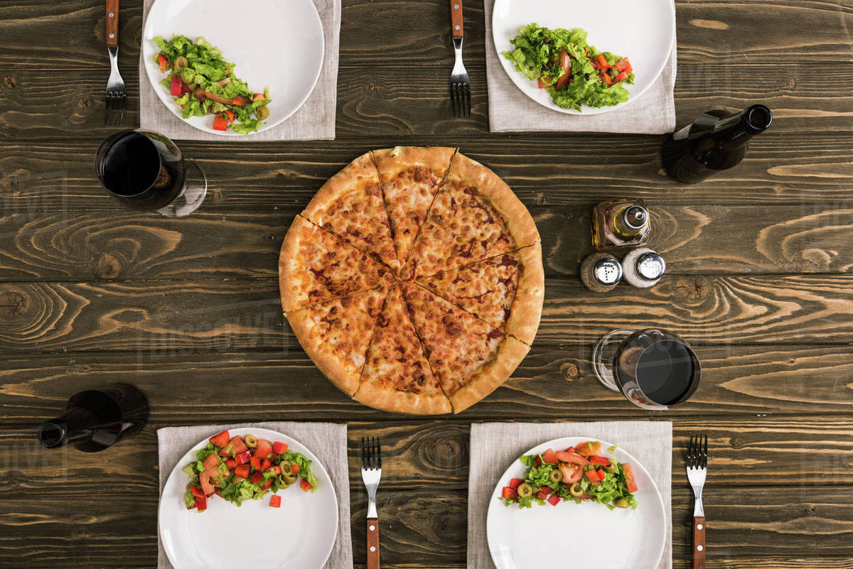 Table setting with pizza and glasses of wine on wooden table Stock