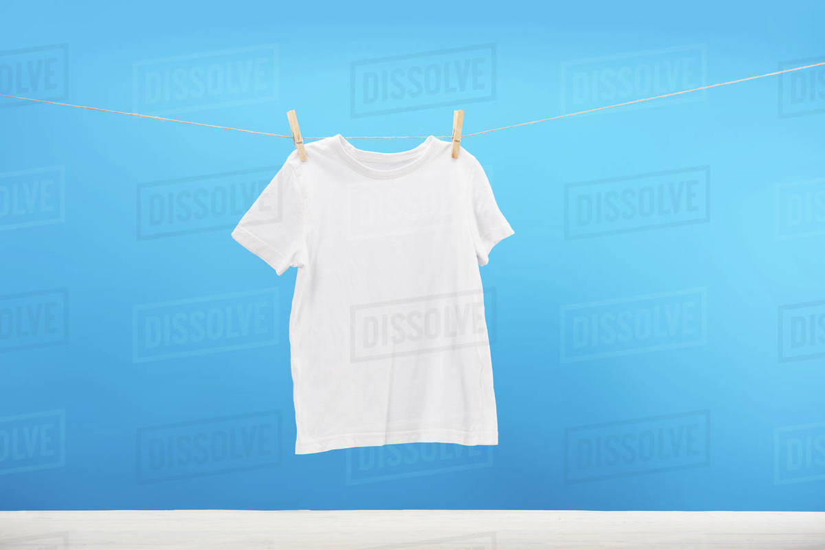 Clean white tshirt hanging on clothesline on blue Stock Photo Dissolve