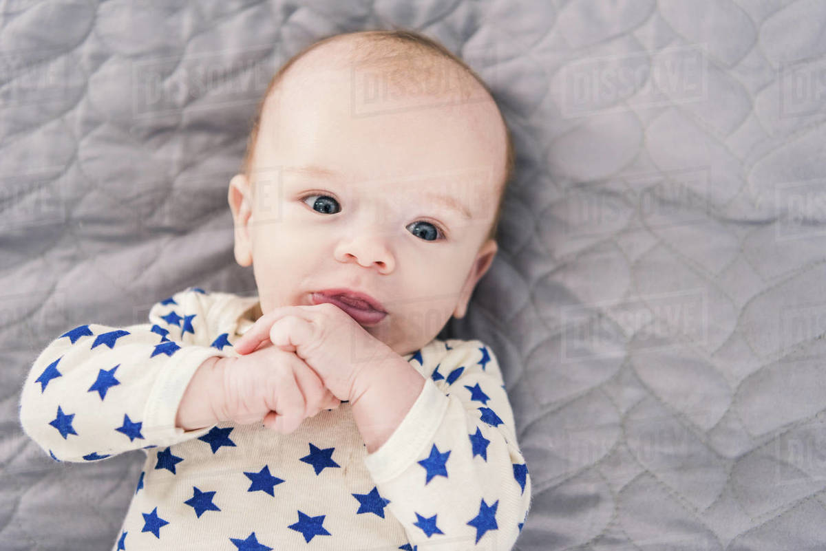 Overhead view of adorable little baby lying on grey blanket Stock
