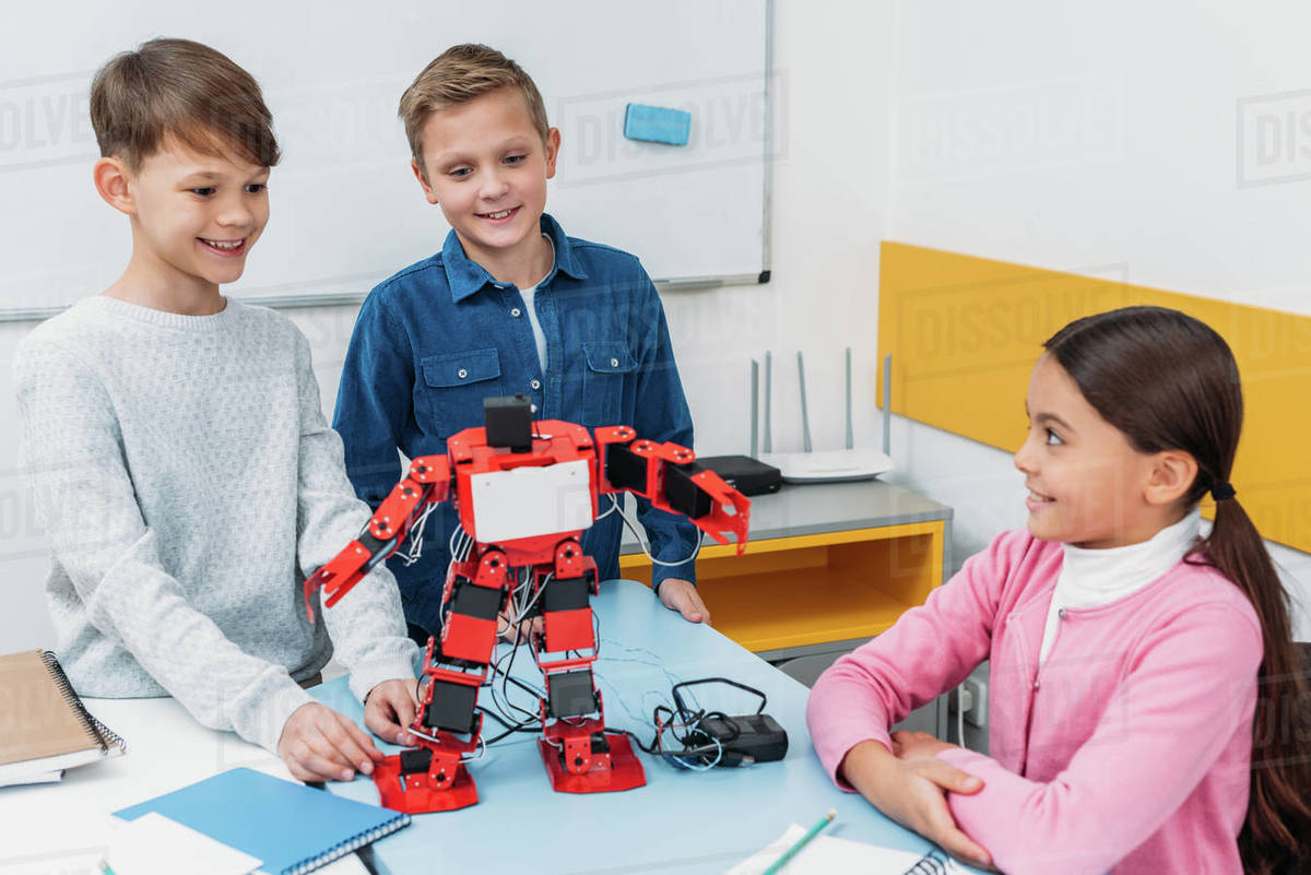 Happy schoolchildren programming robot together during stem educational ...