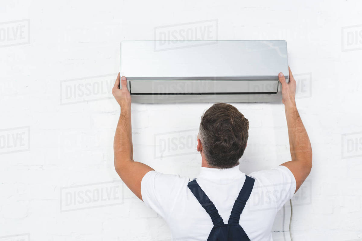 Back view of repairman fixing air conditioner Stock Photo Dissolve
