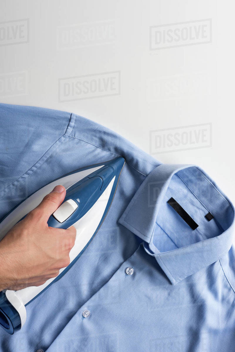 Cropped shot of man ironing blue male shirt Stock Photo Dissolve