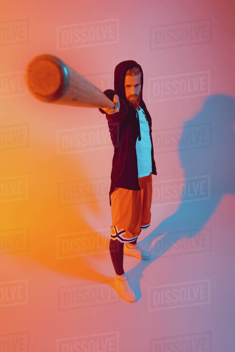 toned picture of handsome man pointing at camera with baseball bat in hand Stock Photo Dissolve