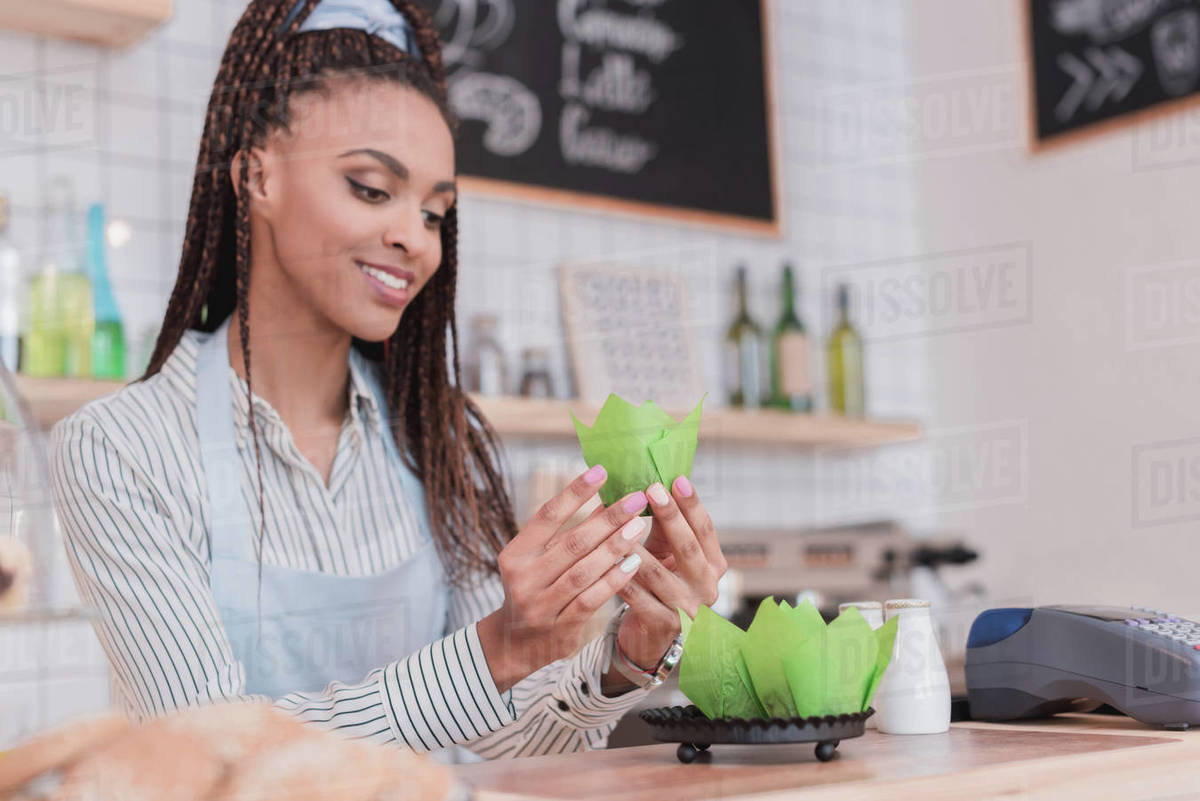 Smiling african american barista wrapping muffins in a coffee shop Stock Photo Dissolve