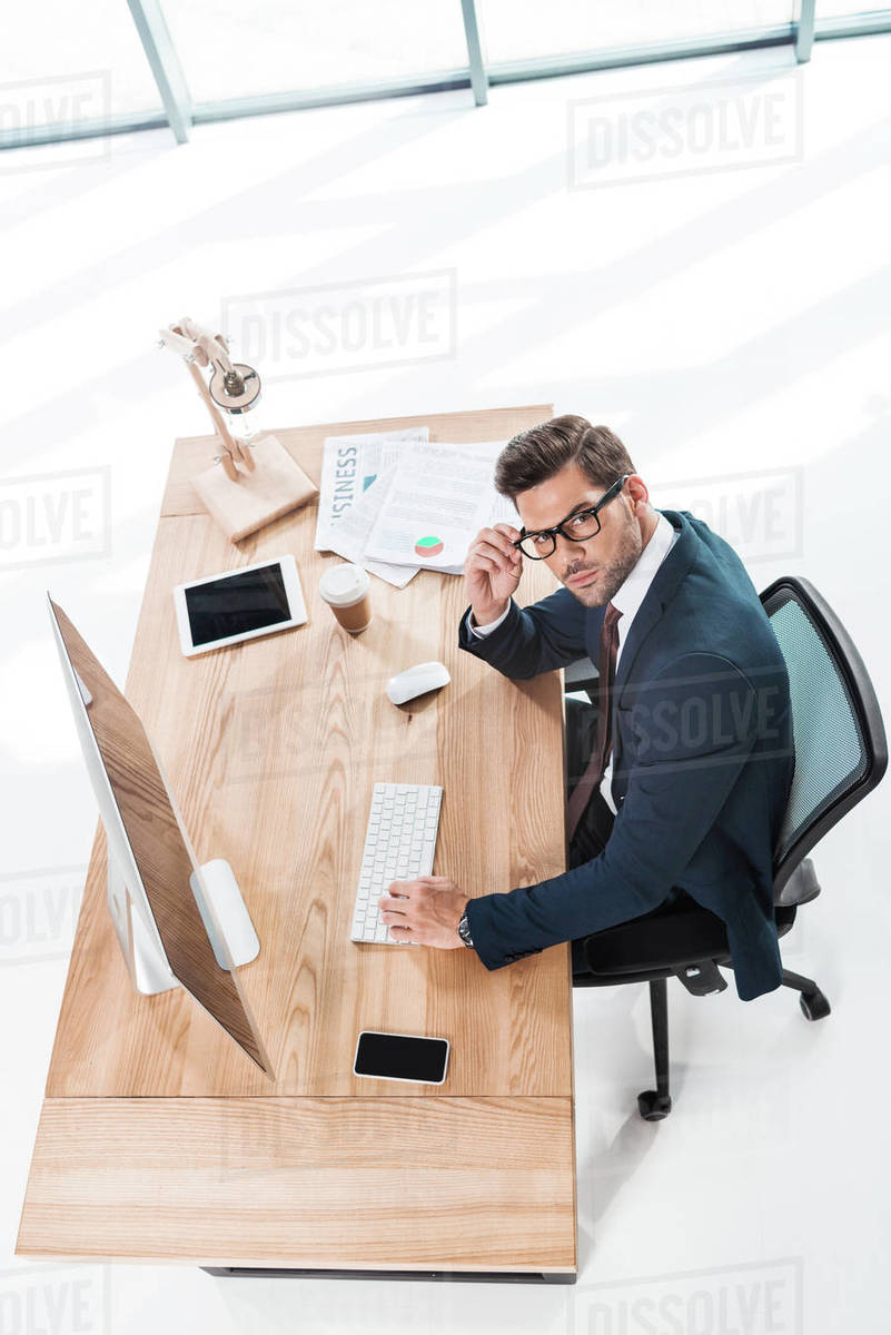 High angle view of young businessman using desktop computer and looking ...