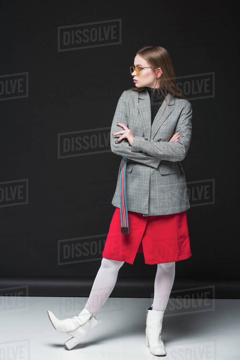 Beautiful woman standing in gray jacket, red skirt and silver shoes