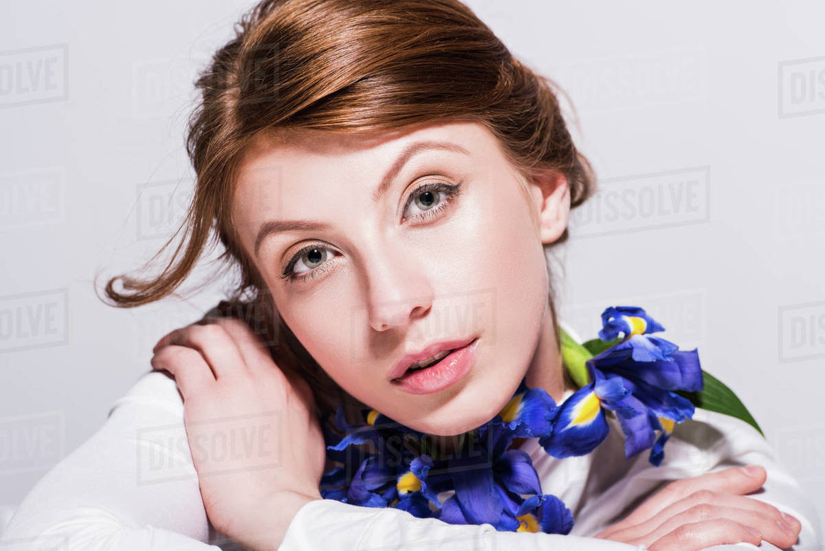 young woman with iris flowers around neck looking at camera isolated on grey Stock