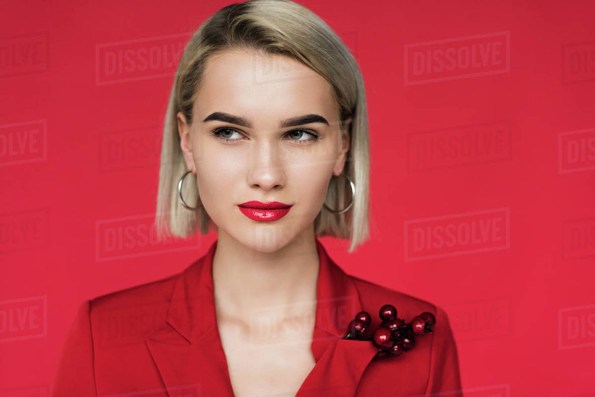 Attractive girl in red suit with boutonniere, isolated on red Stock