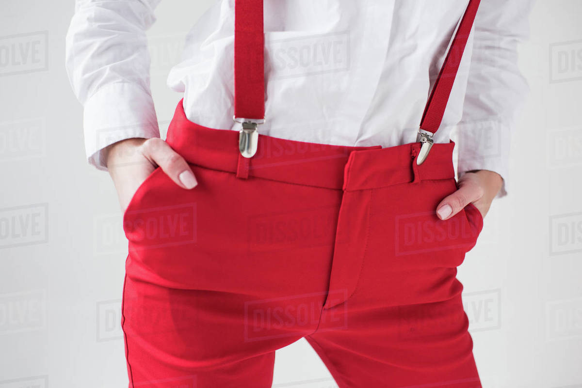 Cropped view of fashionable girl posing in white shirt and red suspenders and pants, isolated on
