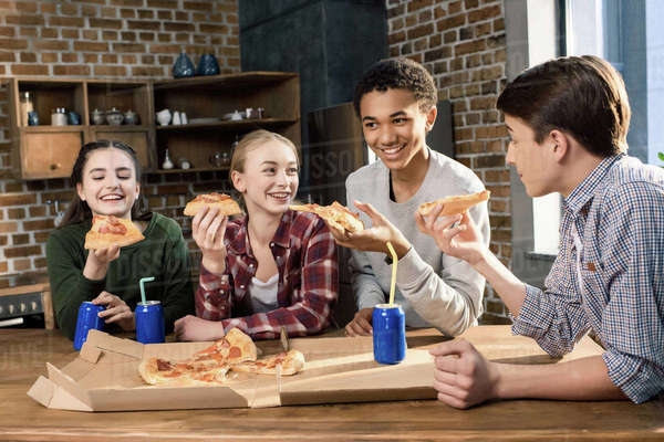 Happy friends spending time together with pizza and soda drinks, eating ...