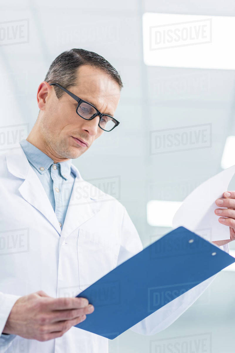 male doctor in white coat reading diagnosis in hospital Stock Photo