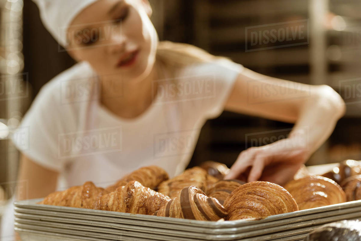 Closeup shot of young female baker doing examination of freshly baked
