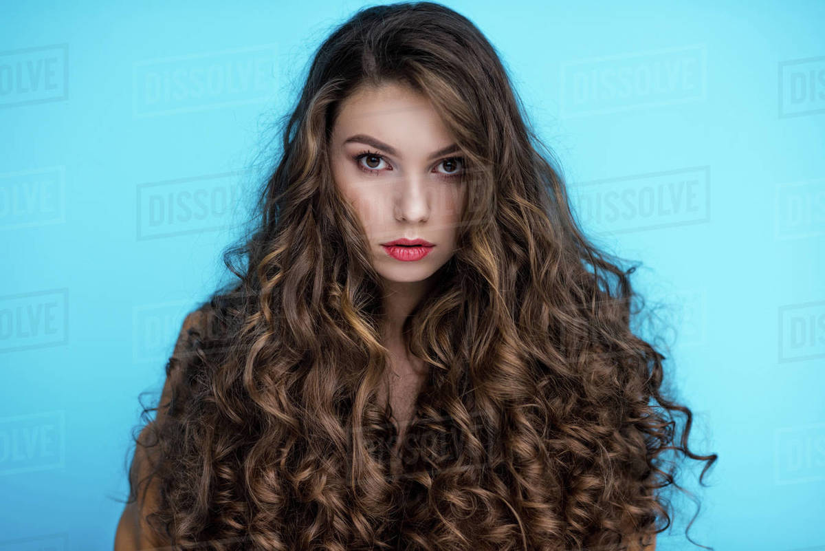 Attractive Young Woman With Long Curly Hair Isolated On Blue
