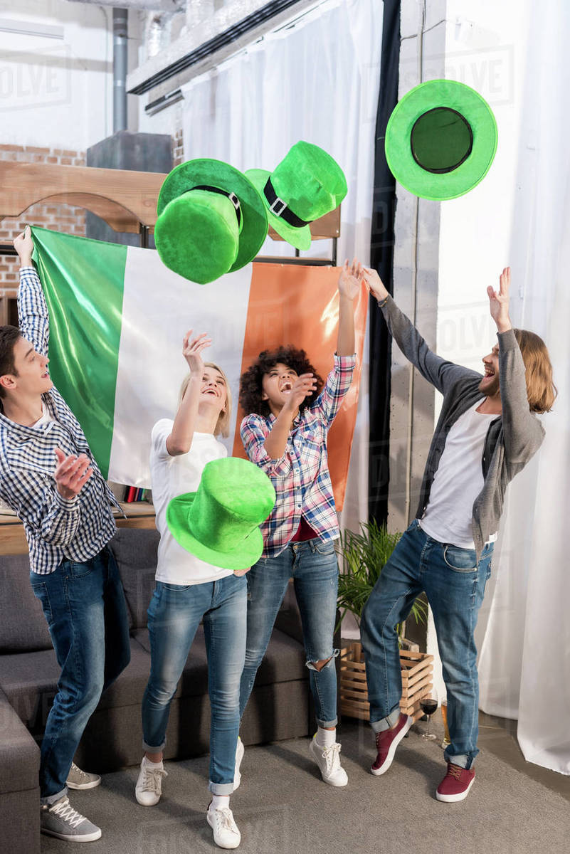 Multicultural friends throwing up green hats on Patrick's day Stock