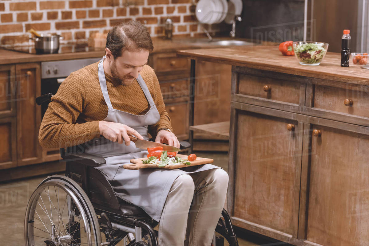 high angle view of disabled man in wheelchair cutting vegetables at