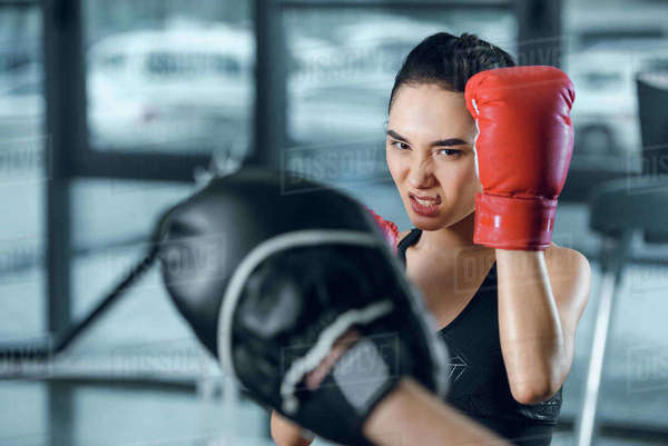 female boxer exercising with trainer at gym - Stock Photo - Dissolve