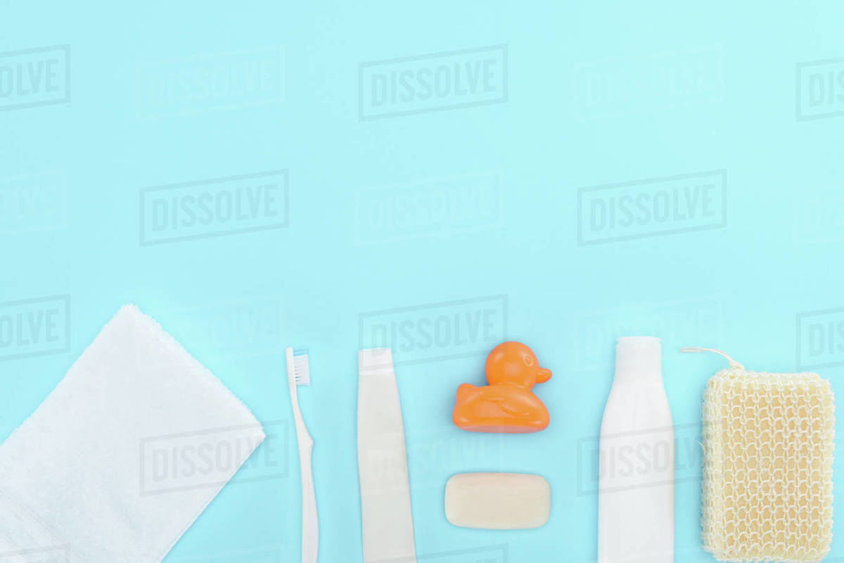 Top view of body lotion, toothbrush, toothpaste, towel, soap and toy