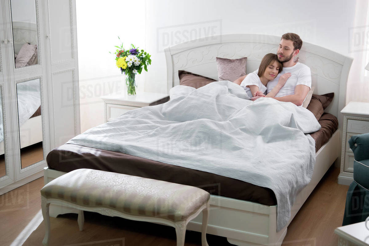 Young Female Lying On Her Boyfriend Chest In Cozy Bedroom Stock Photo Young Female Lying On Her Boyfriend Chest In Cozy Bedroom Stock Photo