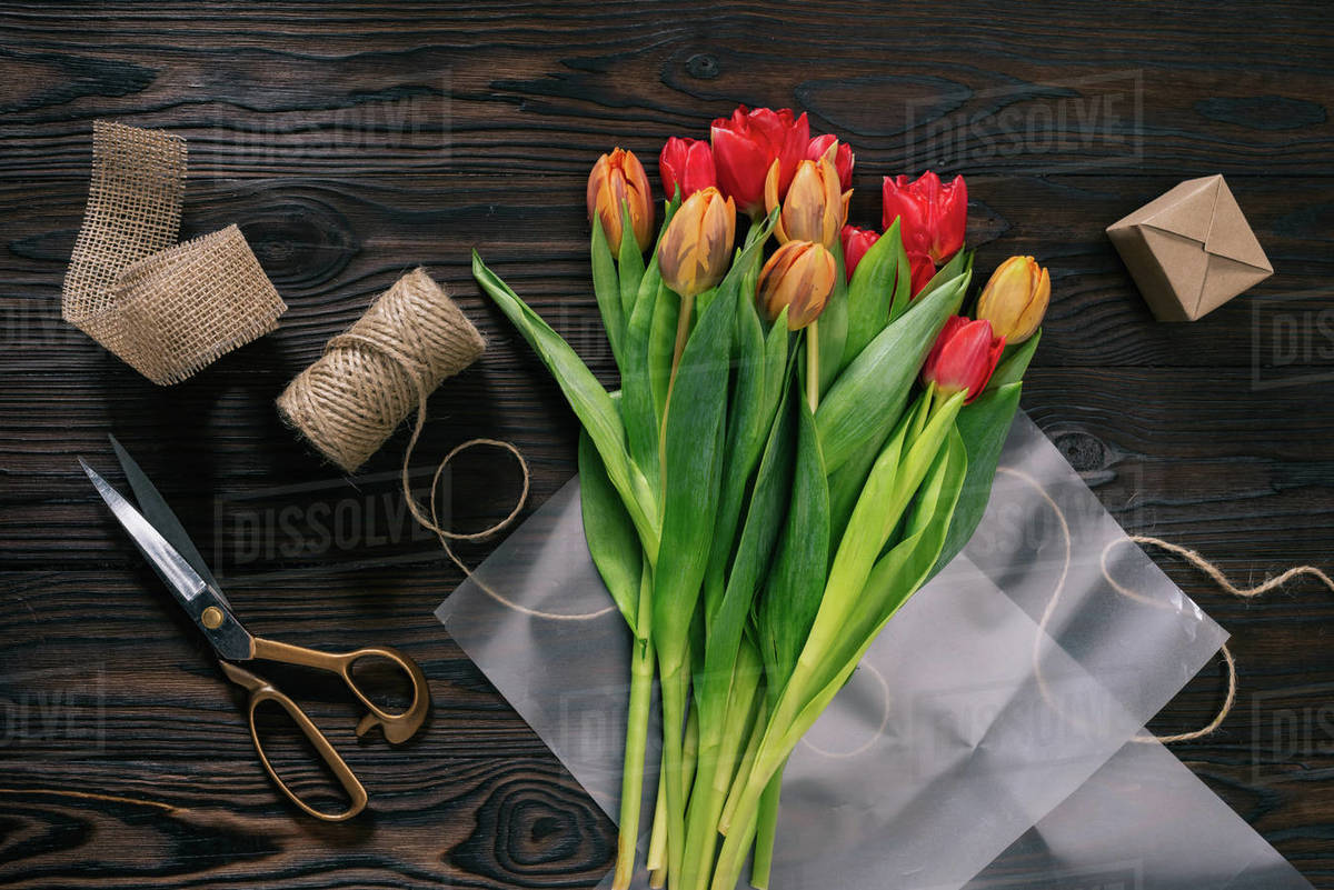 Top view of arranged tulips, rope, scissors and ribbon for decoration ...