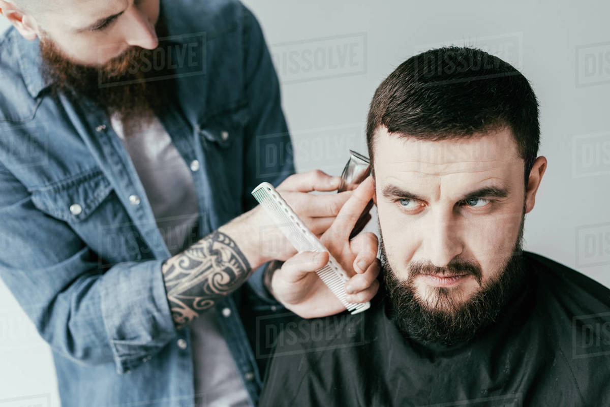 barber shaving customer hair with shaving machine at