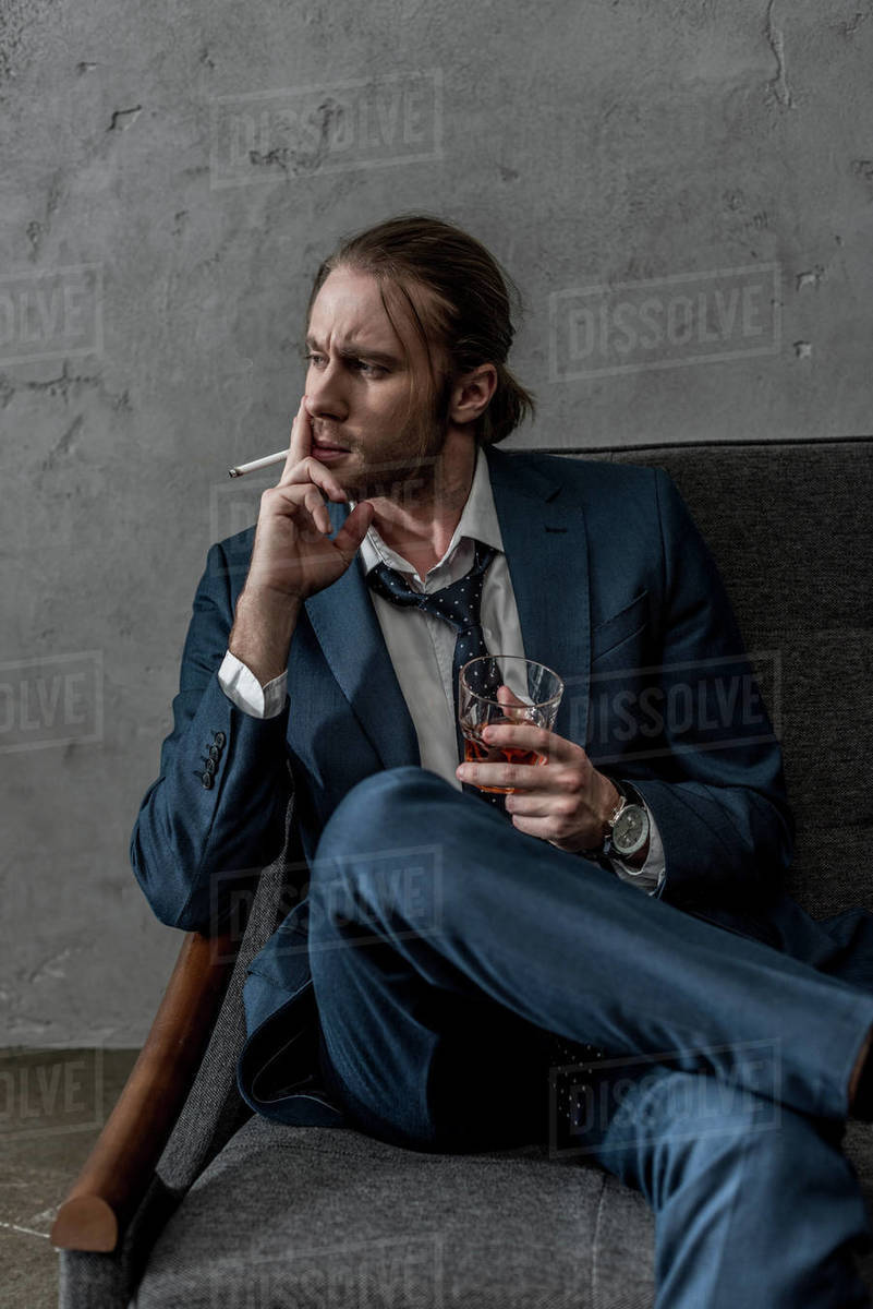 Young alcohol addicted businessman with glass of whiskey smoking cigarette  - Royalty-free Stock Photo