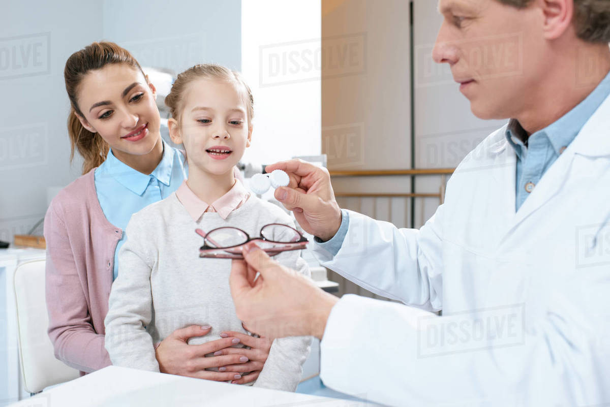Mother and daughter visiting optometrist and choosing eyeglasses or contact lenses in clinic